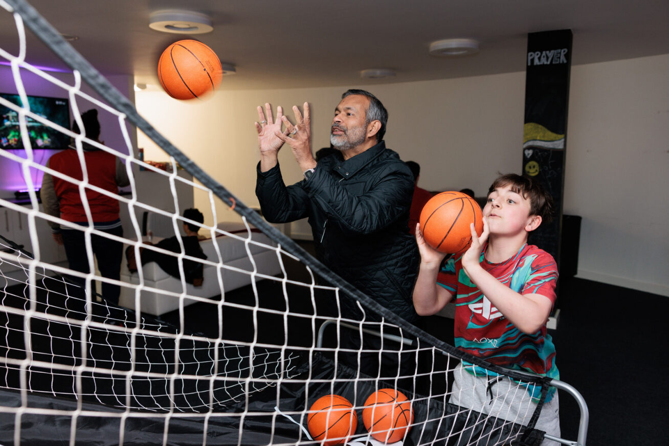 Bishop John shooting basketballs with a young boy at St James in the City